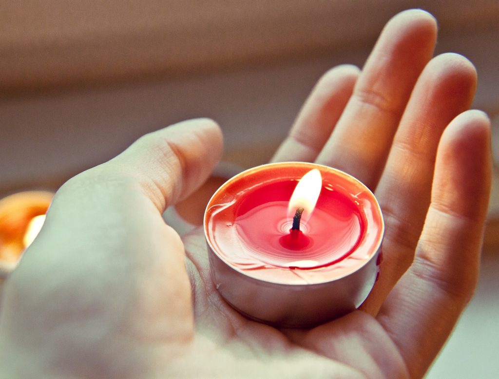 Main tenant une bougie rouge orangée